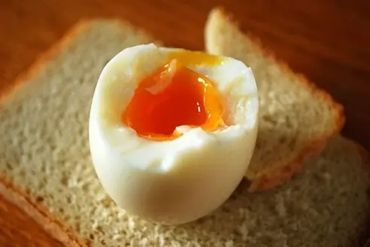 Uovo alla coque con il tuorlo morbido accanto a una fetta di pane